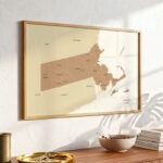 Massachusetts map print displayed on a wooden wall shelf surrounded by subtle decorative objects in natural morning light.