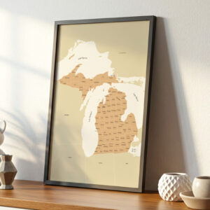 Framed Michigan county map print resting on a wooden console table with decorative ceramic vases and soft window light.