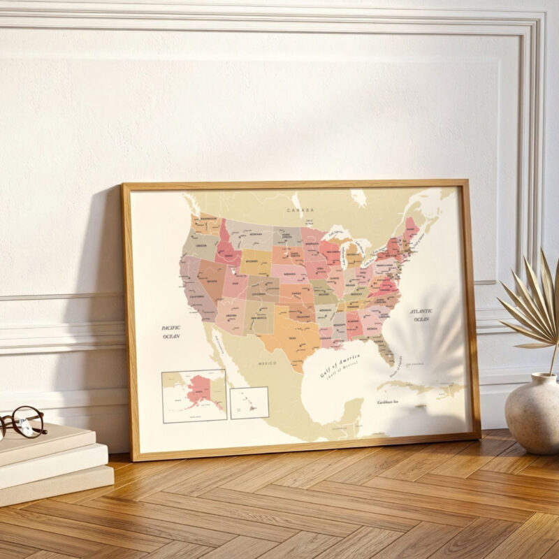 A framed United States map resting on a herringbone wood floor, positioned against a decorative wall with soft natural lighting.